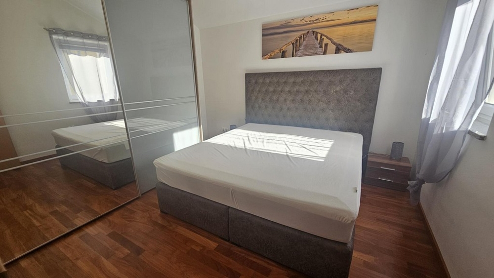 Sypialnia z podwójnym łóżkiem i dużą szafką z lustrem