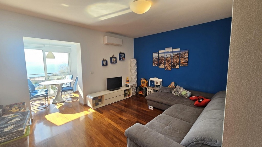 Część dzienna z szarą narożną kanapą i niebieską ścianą