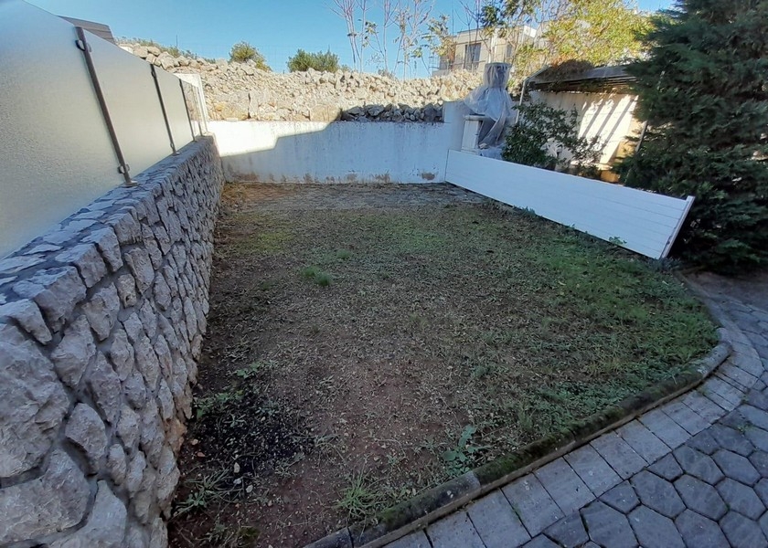 Mały ogród z kamiennym murem i trawnikiem