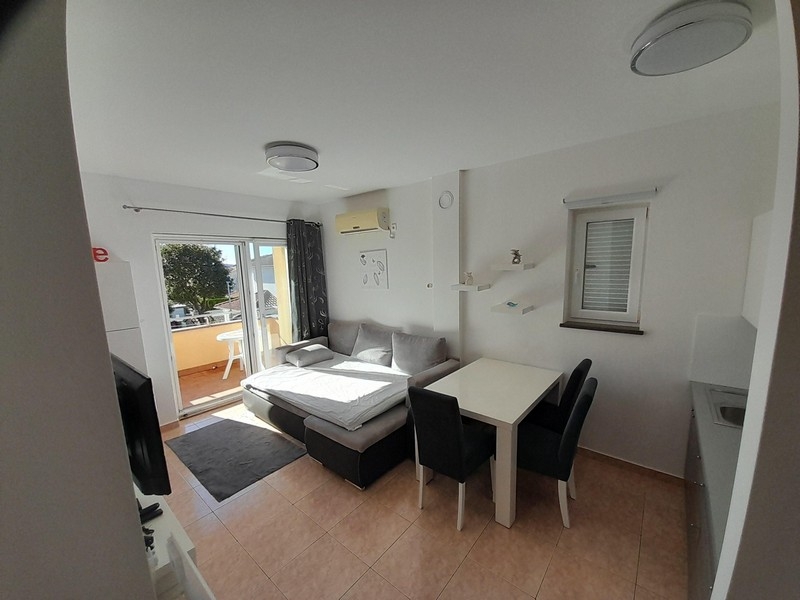 Część dzienna z sofą, stołem jadalnym i dostępem do balkonu z widokiem na morze