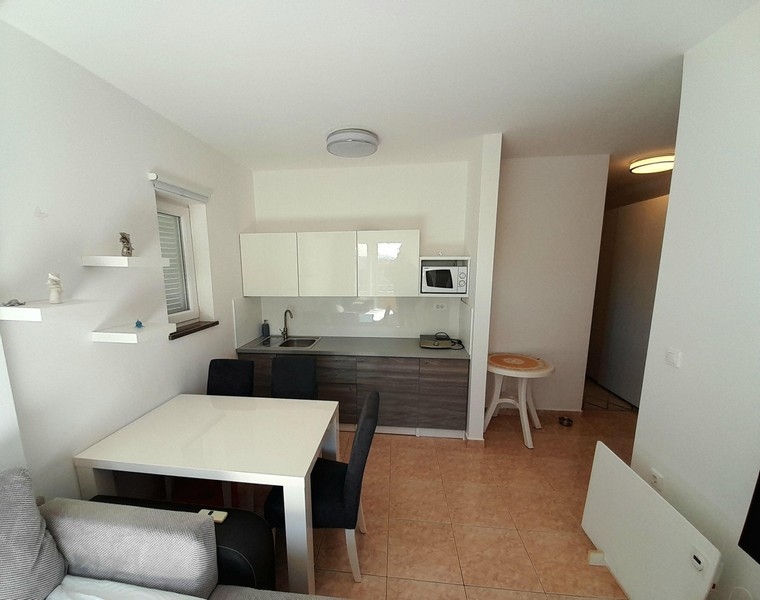 Jasny salon i kuchnia z podłogą wyłożoną kafelkami i dostępem do korytarza