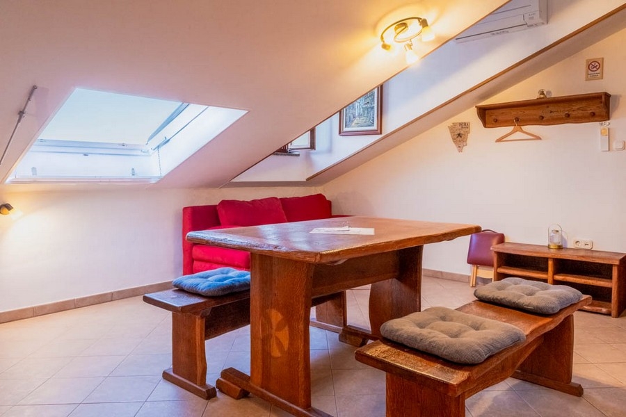 Część dzienna ze skośnym sufitem i drewnianymi meblami