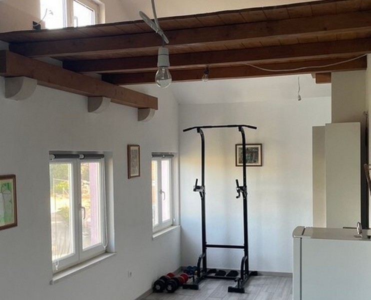 Strefa fitness pod drewnianymi belkami w salonie