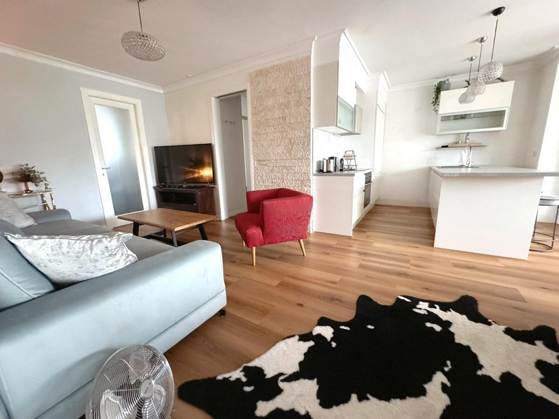 Część dzienna z sofą, czerwonym fotelem i otwartą kuchnią