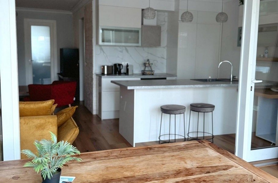 Drewniany stół i widok na białą kuchnię