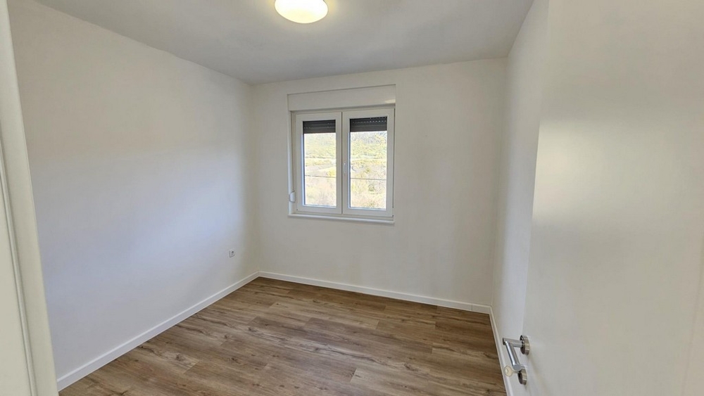 Sypialnia z oknem i drewnianą podłogą