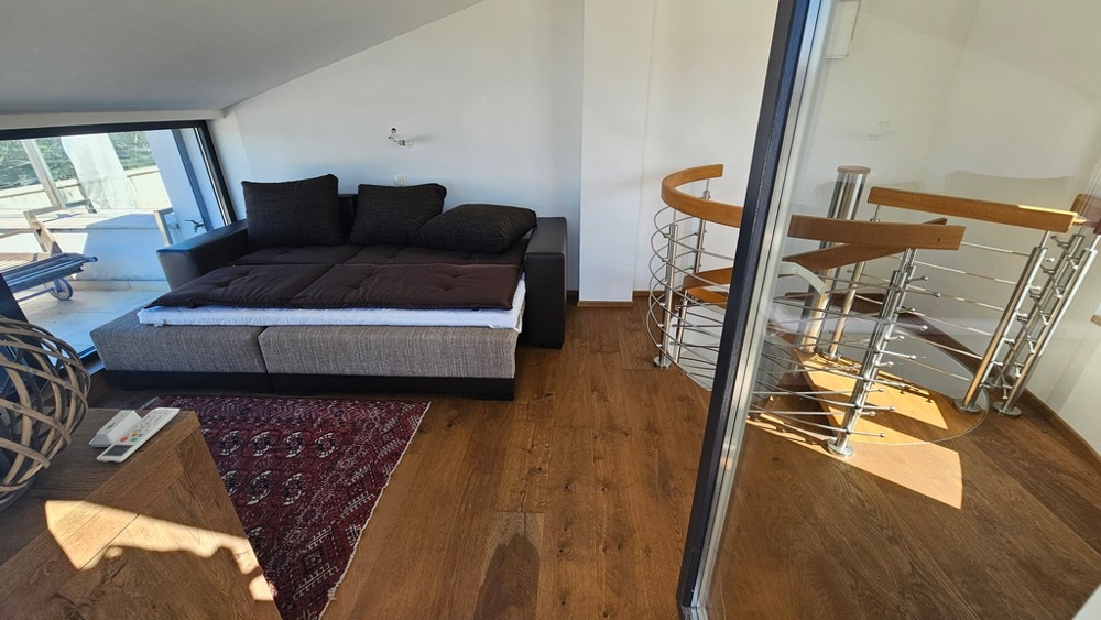 Galeria z sofą i kręconymi schodami na niższy poziom