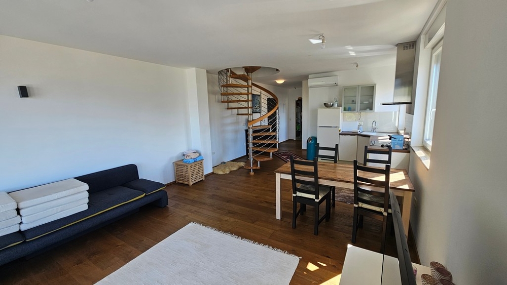 Otwarty salon i jadalnia z kuchnią i kręconymi schodami