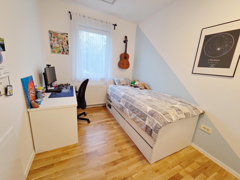 Pokój młodzieżowy z biurkiem, łóżkiem i gitarą na ścianie