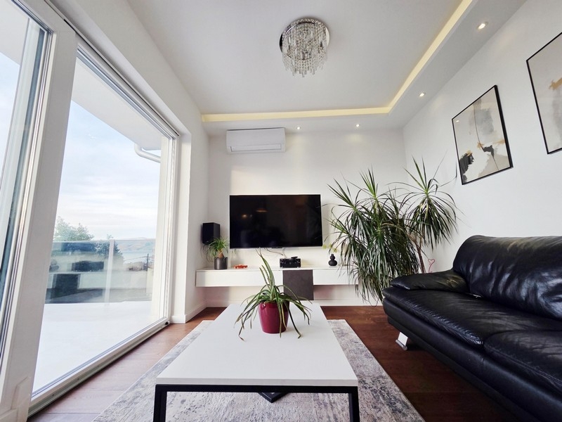 Pokój dzienny z dużym przeszklonym frontem i wyjściem na taras z widokiem na morze