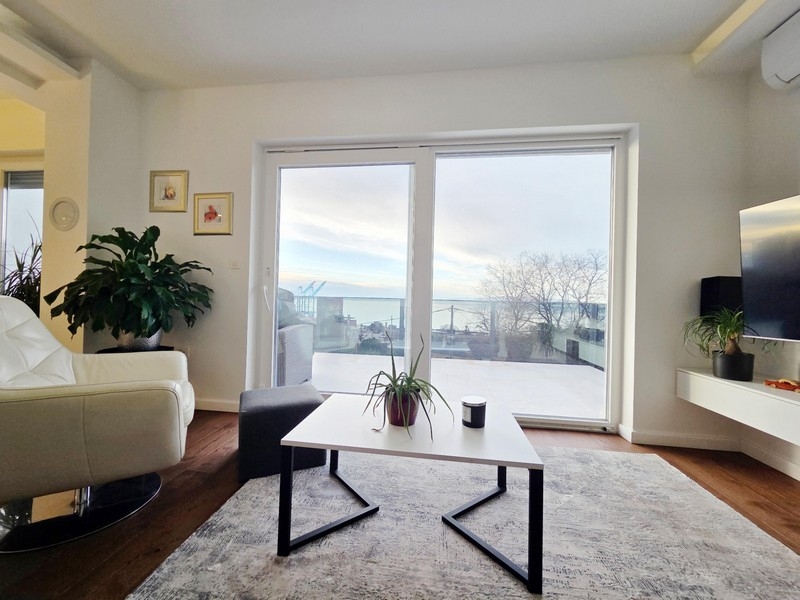 Jasny salon z przesuwanymi drzwiami i widokiem na miasto i morze