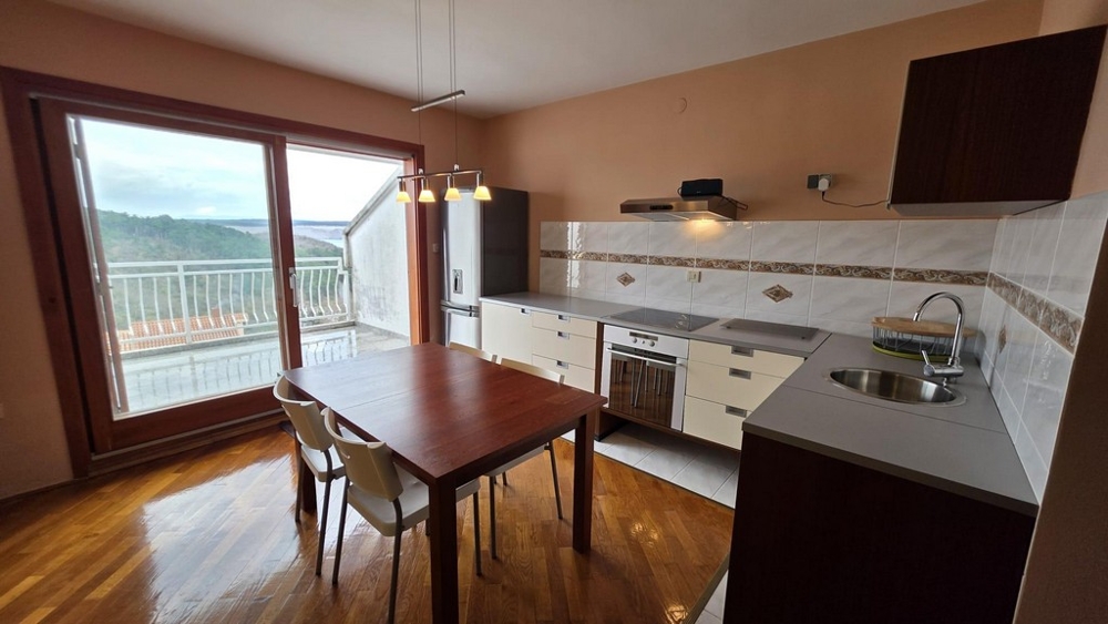 Część dzienna ze zintegrowanym aneksem kuchennym i widokiem na taras.