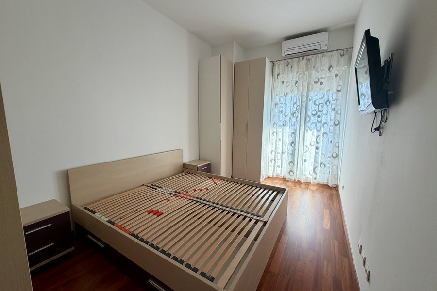 Sypialnia z zabudowaną szafą, na podłodze parkiet i wyjście na balkon