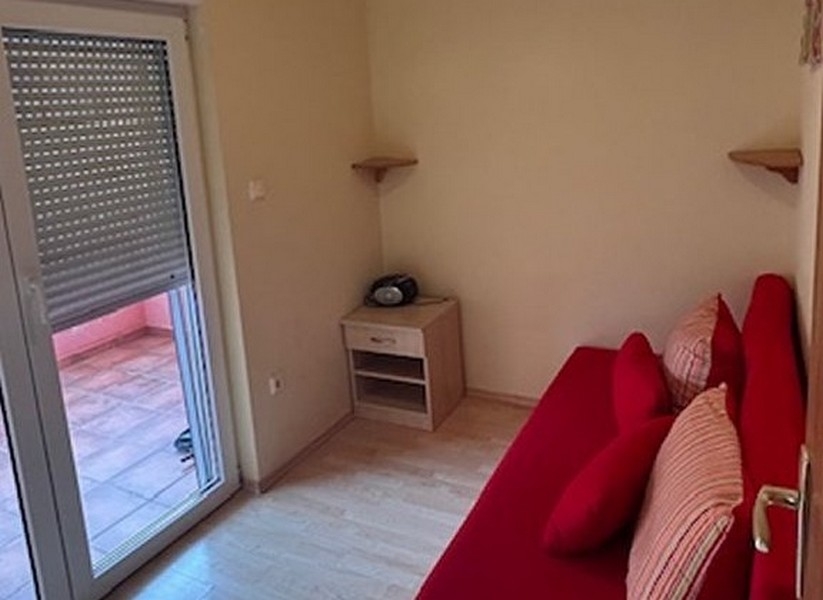 Sypialnia z czerwoną sofą i dostępem do balkonu