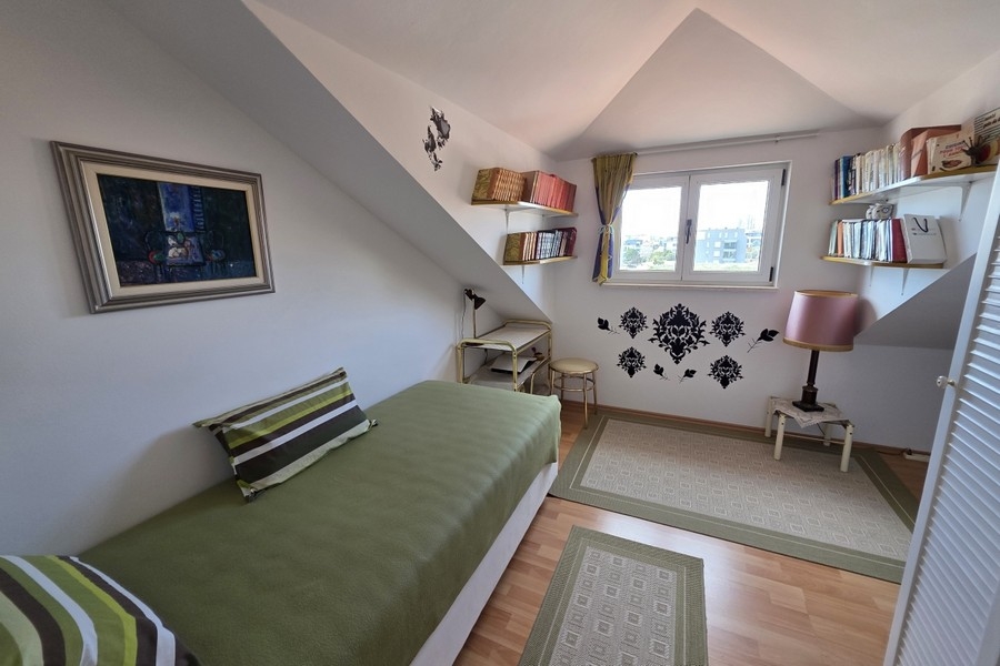 Jasna sypialnia na poddaszu z łóżkiem pojedynczym, miejscem do pracy i skośnymi sufitami