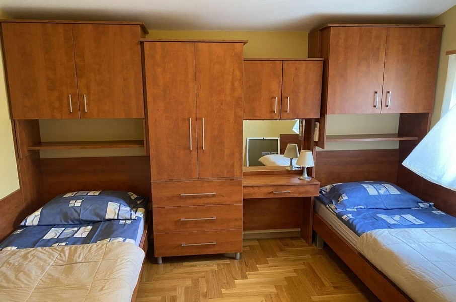 Sypialnia z pojedynczymi łóżkami i drewnianymi meblami w apartamencie wakacyjnym