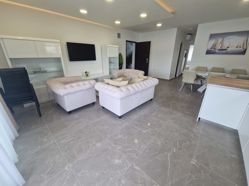 Otwarta część dzienna z kuchnią i widokiem na morze w nowoczesnym apartamencie