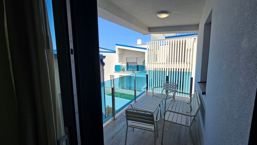 Zadaszony balkon ze szklanymi balustradami i częścią wypoczynkową