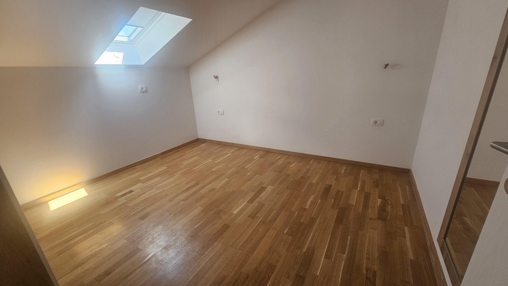 Pokój ze świetlikiem i drewnianą podłogą