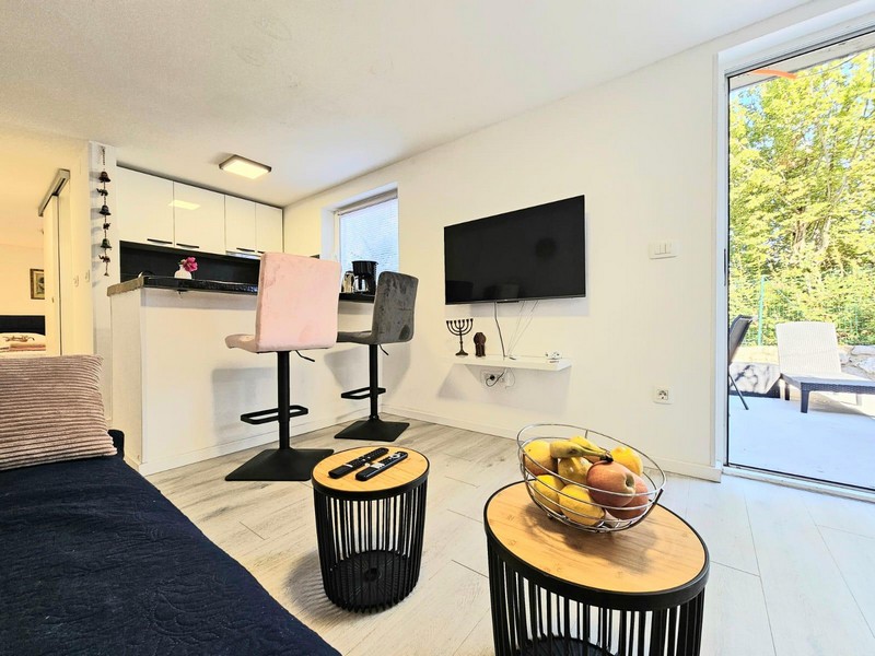 Umeblowany salon z telewizorem i stołkami barowymi w Njivice