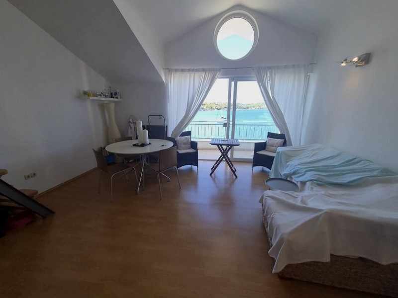 Jasny salon pod spadzistym dachem z okrągłym oknem