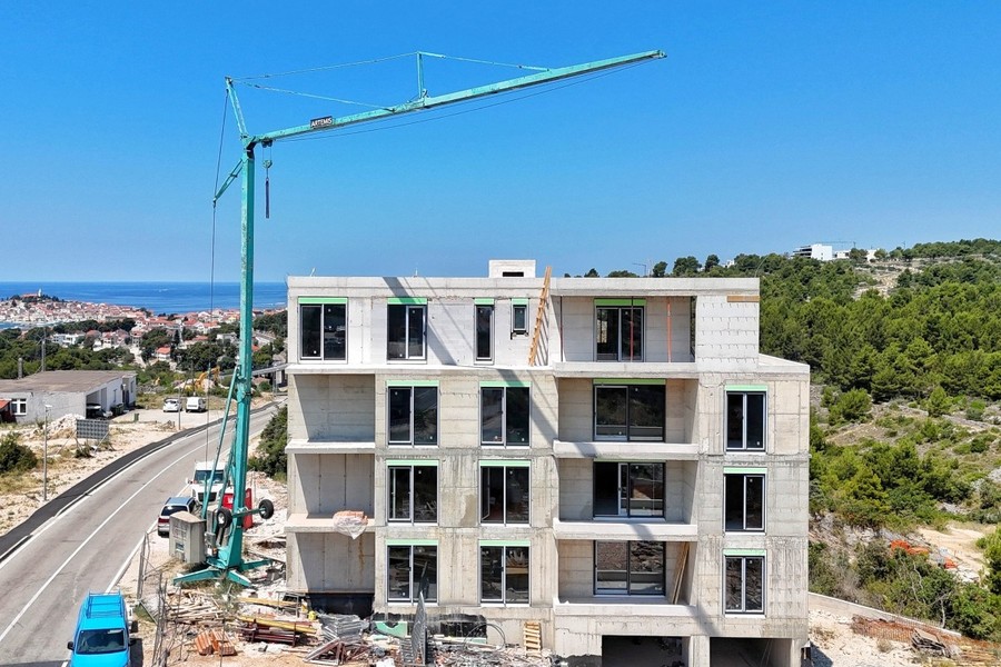 Plac budowy z dźwigiem, po lewej stare miasto nad morzem