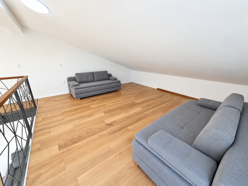 Galeria z drewnianą podłogą pod skosem dachu