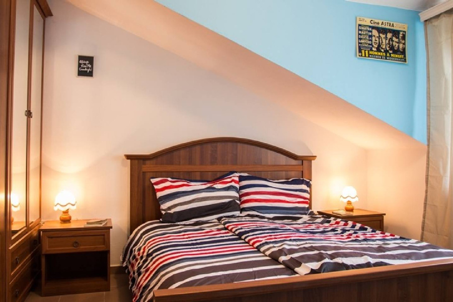 Sypialnia na poddaszu z podwójnym łóżkiem i oknem w regionie Pula.