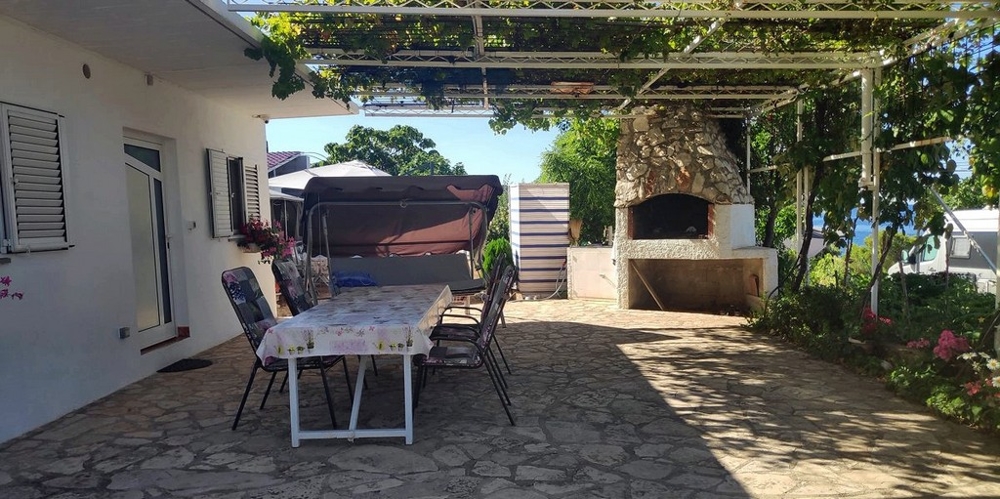 Taras z zadaszoną jadalnią i grillem.