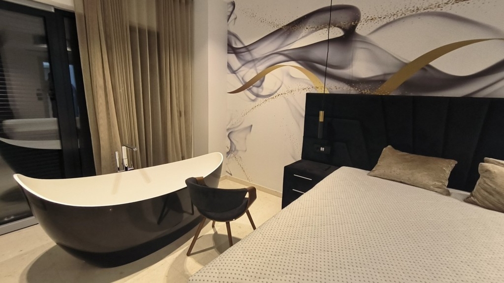 Sypialnia z wolnostojącą wanną i stylową ścianą