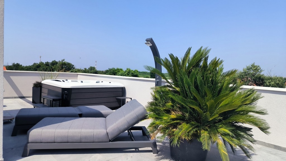 Taras na dachu z leżakiem, jacuzzi i widokiem na okolicę.