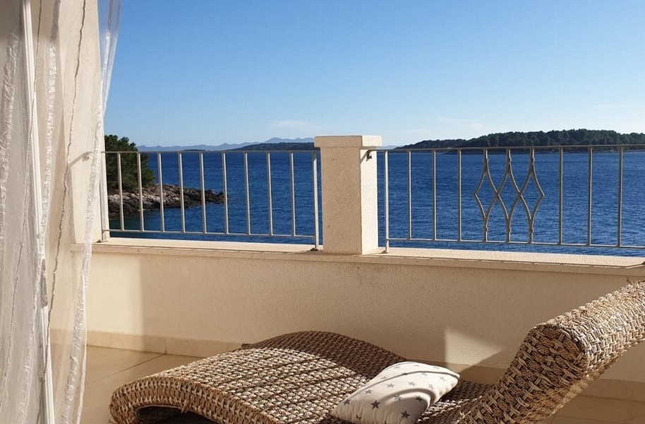 Taras z widokiem na morze i relaksującym wiklinowym leżakiem.