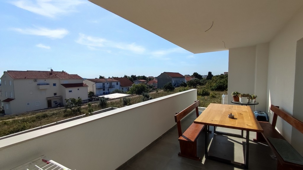 Przestronny balkon z jadalnią domu rodzinnego w Vodicach w Chorwacji, z widokiem na spokojną okolicę.