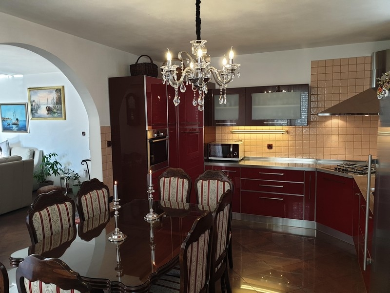 Elegancka jadalnia z czerwono-brązową kuchnią w apartamentowcu w Chorwacji
