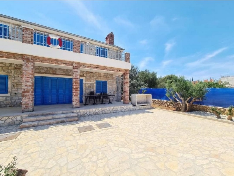 Widok z przodu uroczego kamiennego domu na sprzedaż w Chorwacji z jadalnią na świeżym powietrzu.