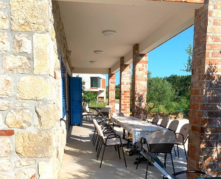 Zadaszona jadalnia na świeżym powietrzu w kamiennym domu na sprzedaż w Chorwacji, idealna na spotkania.