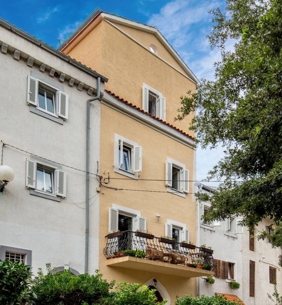 Fasada żółtego domu jako część nieruchomości w Chorwacji z balkonami i okiennicami