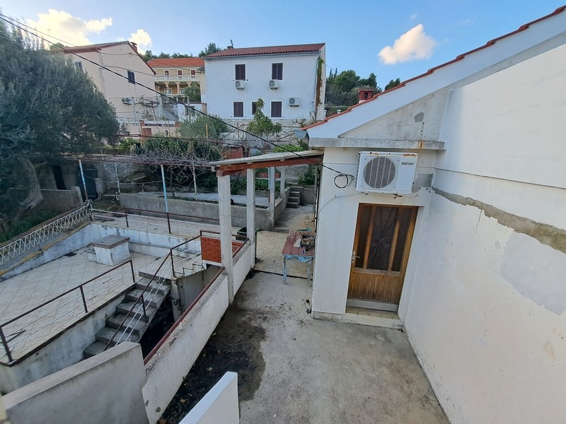 Część podwórkowa chorwackiej nieruchomości z zadaszonym tarasem i schodami, wystawiona na sprzedaż przez Panorama Scouting.