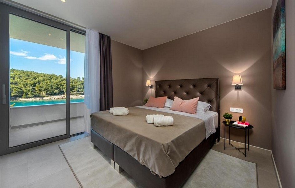 Sypialnia z podwójnym łóżkiem, nowoczesnym designem i widokiem na morze w willi na Bracu.