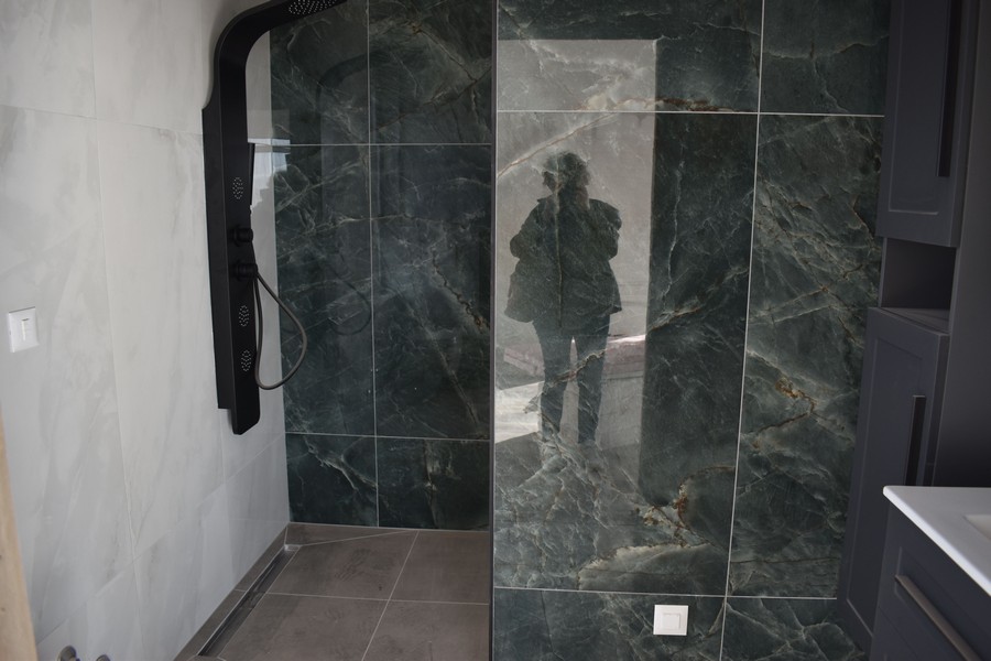 Elegancki prysznic z ciemnymi marmurowymi płytkami w willi na sprzedaż na wyspie Krk w Chorwacji.