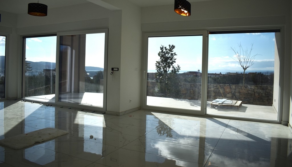 Przestronny, pusty pokój dzienny z białymi ścianami i dużym oknem w willi na Krk.