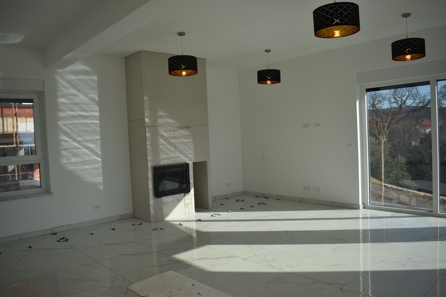 Widok wnętrza salonu z kominkiem i widokiem na przyrodę w willi na Krku.