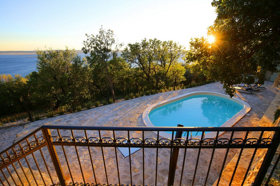 Na sprzedaż basen w chorwackim kamiennym domu, z zachodem słońca i widokiem na morze w tle.