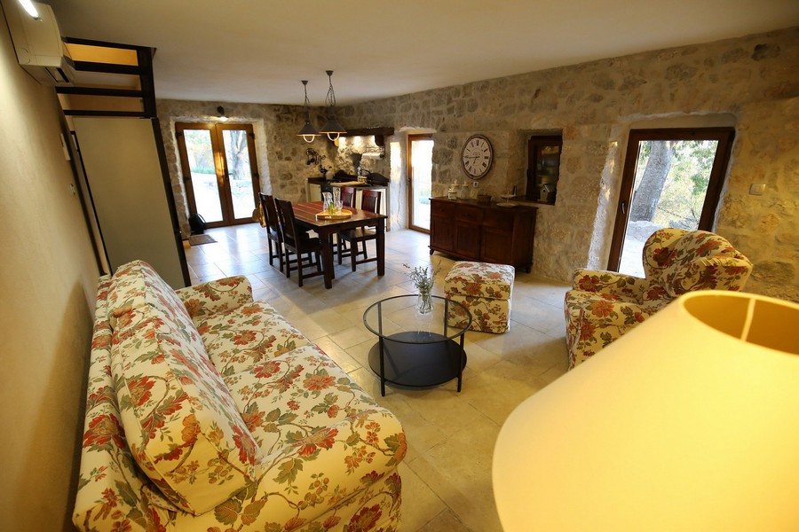 Wnętrze kamiennego domu na sprzedaż w Chorwacji z salonem, jadalnią i rustykalnymi meblami.