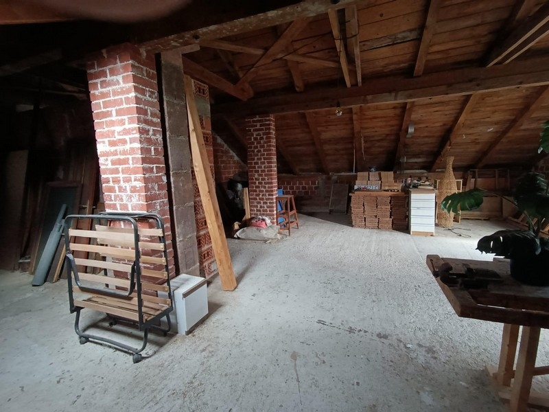 Pokój na poddaszu z odsłoniętymi drewnianymi belkami i cegłami w budynku mieszkalnym na sprzedaż w Crikvenicy w Chorwacji.