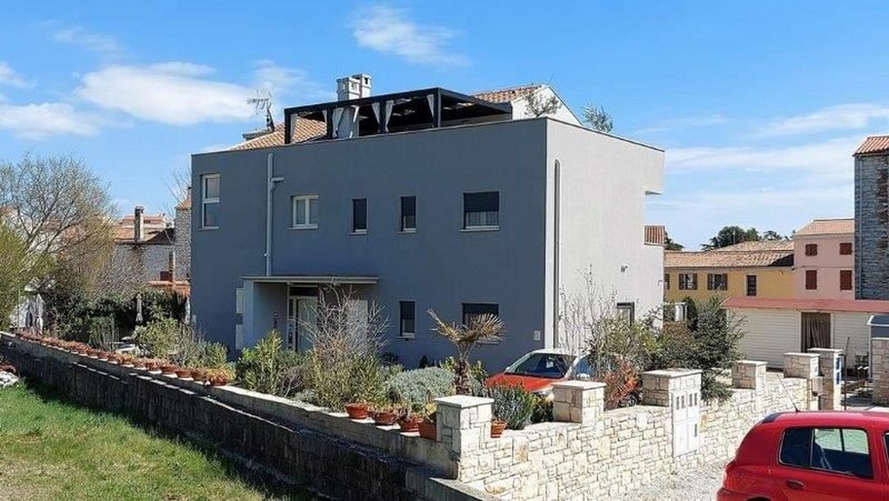 Widok z boku domu z trzema mieszkaniami na sprzedaż na Istrii, z tarasem i dekoracją roślinną wzdłuż płotu.
