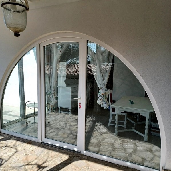 Duży łukowy szklany front willi na sprzedaż na wyspie Cres w Chorwacji, z widokiem na białe wnętrze i widok na morze