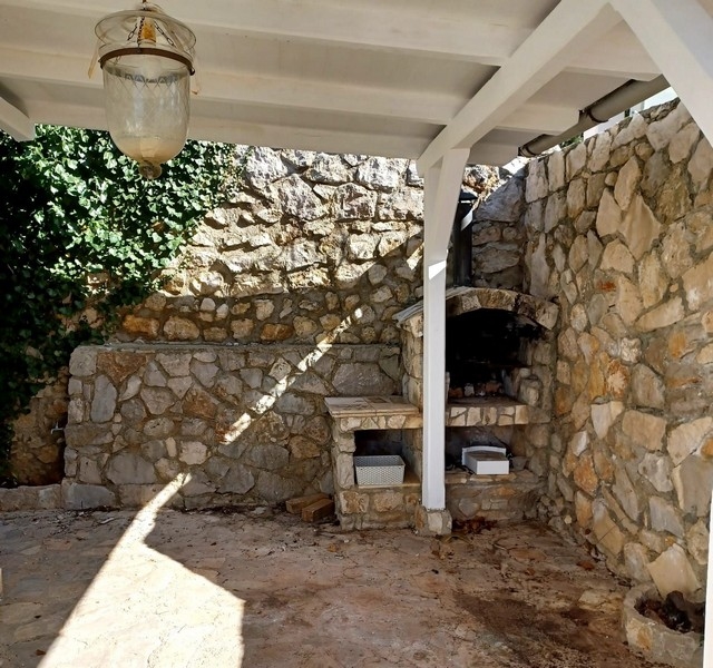 Kuchnia na świeżym powietrzu z tradycyjnym kamiennym piekarnikiem w willi na sprzedaż na wyspie Cres w Chorwacji, pod białym dachem