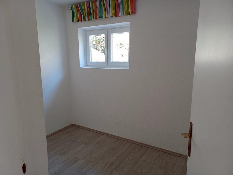 Prosty, pusty pokój z oknem i drewnianą podłogą w willi na sprzedaż na wyspie Cres w Chorwacji