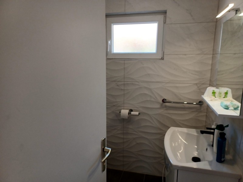 Łazienka z nowoczesnymi falistymi płytkami i białą umywalką w willi na sprzedaż na wyspie Cres w Chorwacji.